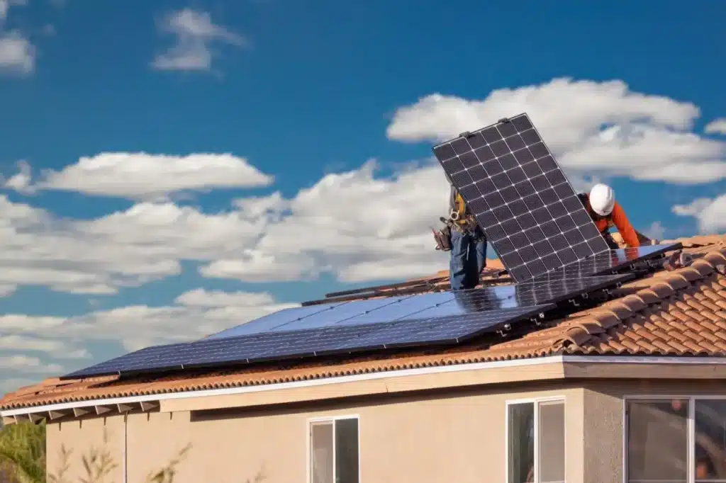Workers from a solar installation company in Massachusetts installing solar panels on the roof of a home